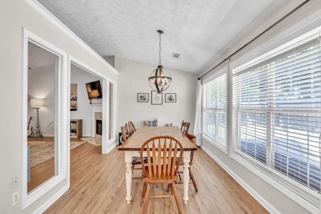 2780 Matlin Way, Buford, GA 30519 - dining area featuring a textured ceiling, a chandelier, light wood finished floors, baseboards, and a fireplace with flush hearth