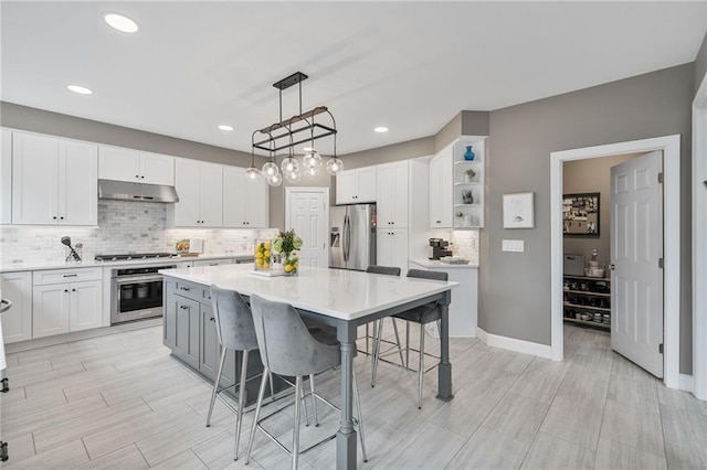 1775 Porterton Way, Cumming, GA 30041 - kitchen with stainless steel appliances, under cabinet range hood, a kitchen breakfast bar, backsplash, and a center island
