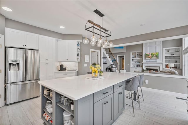 1775 Porterton Way, Cumming, GA 30041 - kitchen featuring stainless steel refrigerator with ice dispenser, open shelves, gray cabinetry, a kitchen island, and white cabinetry