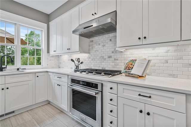 1775 Porterton Way, Cumming, GA 30041 - kitchen with under cabinet range hood, appliances with stainless steel finishes, light countertops, and backsplash