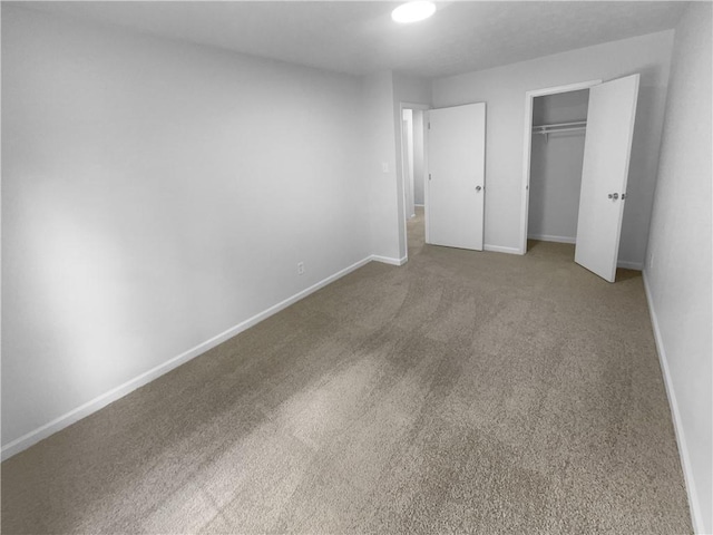 unfurnished bedroom with carpet, a closet, and baseboards