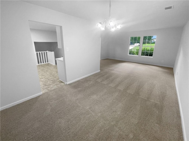 carpeted spare room with a chandelier and baseboards