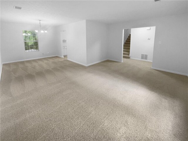 unfurnished room featuring a chandelier, baseboards, light colored carpet, and stairway