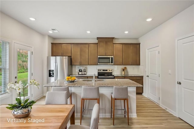 2770 Aralynn Way, College Park, GA 30337 - kitchen with appliances with stainless steel finishes, light wood-style floors, light stone countertops, recessed lighting, and a center island with sink