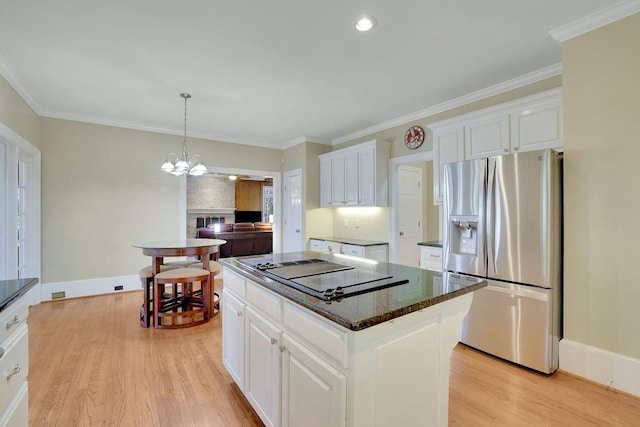 kitchen featuring a center island, white cabinets, stainless steel refrigerator with ice dispenser, and black electric stovetop