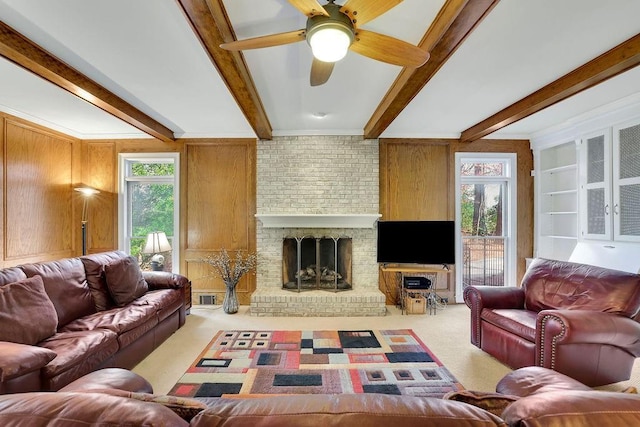 living room with ceiling fan, beamed ceiling, wood walls, carpet floors, and a fireplace