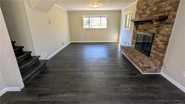 unfurnished living room with dark hardwood / wood-style floors, ornamental molding, and a brick fireplace