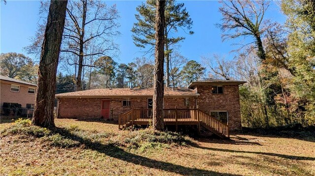 rear view of house with a lawn and a wooden deck