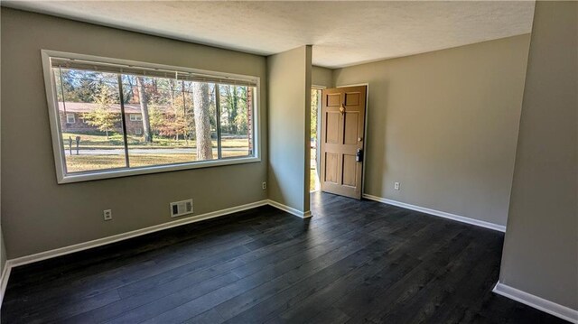 empty room featuring a textured ceiling and dark hardwood / wood-style flooring