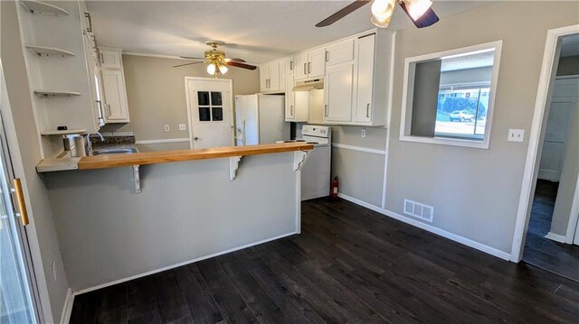 kitchen featuring kitchen peninsula, butcher block countertops, white cabinetry, white fridge with ice dispenser, and a breakfast bar area