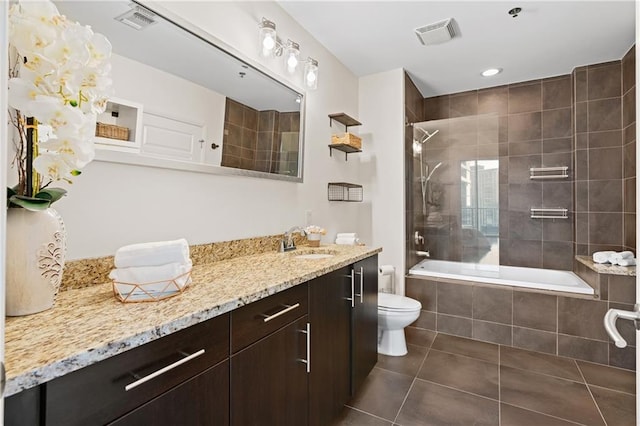 full bathroom with tile patterned flooring, tiled shower / bath, vanity, and toilet