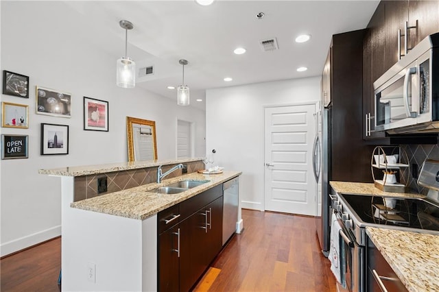 kitchen with dark brown cabinetry, sink, tasteful backsplash, a center island with sink, and appliances with stainless steel finishes