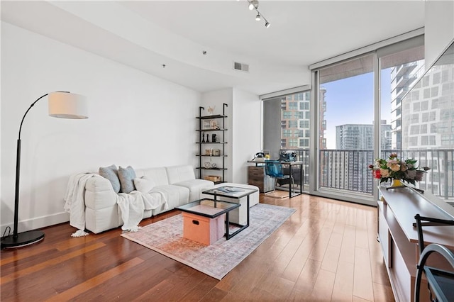 living room with dark hardwood / wood-style flooring, a wall of windows, and rail lighting