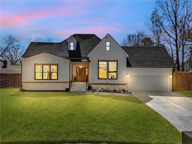 view of front facade featuring a garage, brick siding, fence, driveway, and a lawn