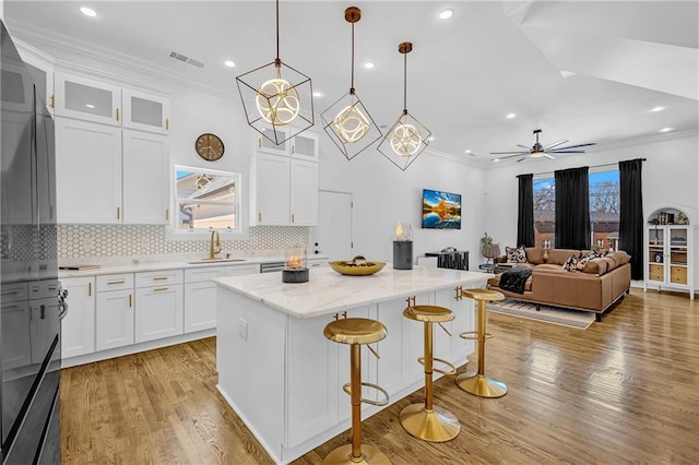 kitchen featuring light wood-type flooring, crown molding, a sink, and a center island