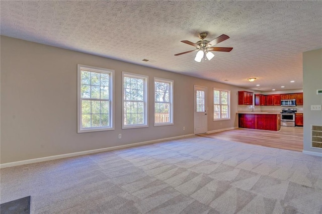 unfurnished living room featuring a textured ceiling, ceiling fan, and light carpet