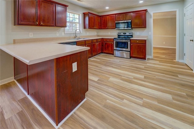 kitchen featuring kitchen peninsula, sink, stainless steel appliances, and light hardwood / wood-style floors