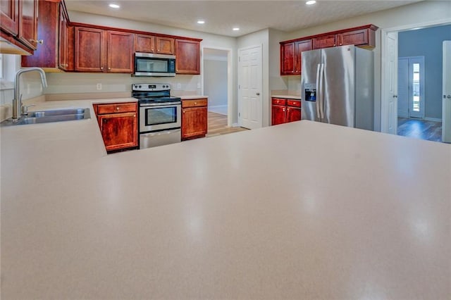 kitchen featuring kitchen peninsula, stainless steel appliances, sink, light hardwood / wood-style floors, and plenty of natural light