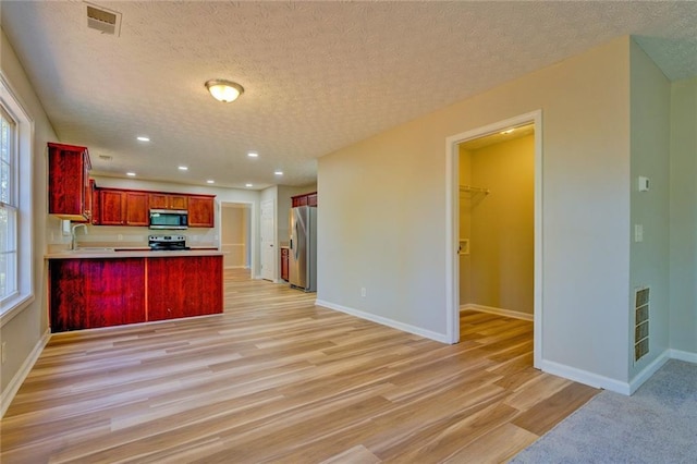 kitchen with a textured ceiling, sink, kitchen peninsula, and stainless steel appliances