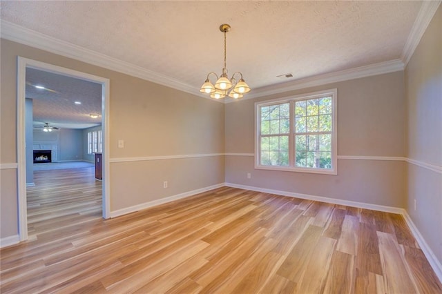 spare room featuring ceiling fan with notable chandelier, a textured ceiling, light hardwood / wood-style flooring, and crown molding