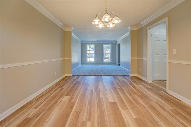 unfurnished room featuring ornamental molding, light wood-type flooring, and an inviting chandelier