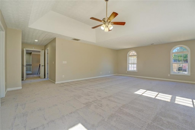 spare room with a tray ceiling, ceiling fan, and plenty of natural light