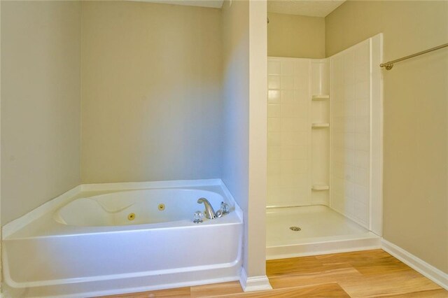 bathroom featuring wood-type flooring and shower with separate bathtub