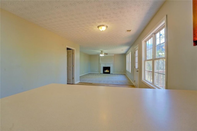 unfurnished living room featuring a textured ceiling and ceiling fan