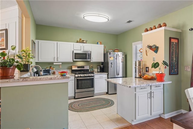 kitchen with visible vents, stainless steel appliances, a peninsula, and white cabinetry