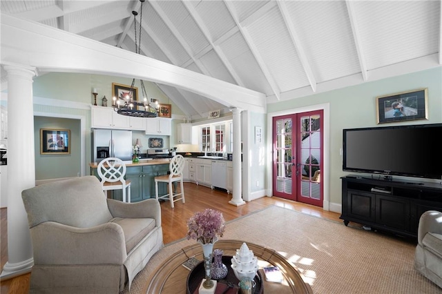 living area featuring french doors, decorative columns, light wood finished floors, a chandelier, and baseboards