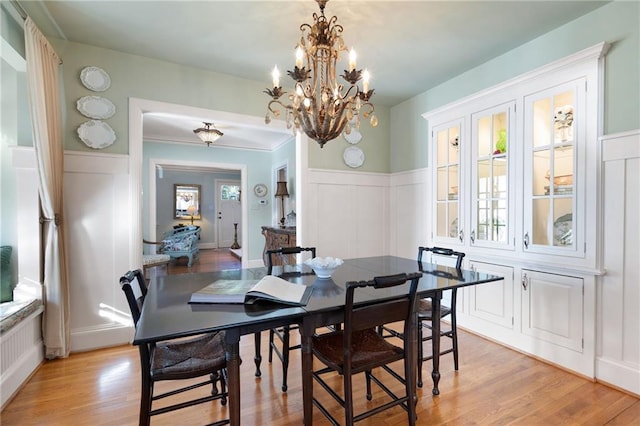 dining area featuring a wainscoted wall, a decorative wall, and light wood-style floors