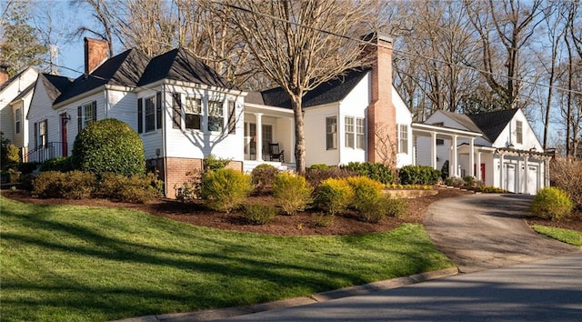 view of front of house with a garage, brick siding, driveway, a chimney, and a front yard