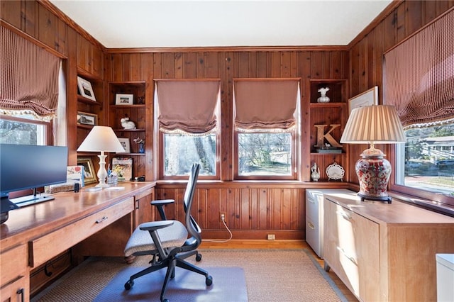 home office with built in features, light wood-style flooring, and wooden walls