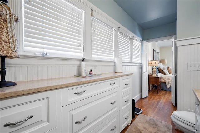 interior space with light stone counters, wood finished floors, and white cabinets