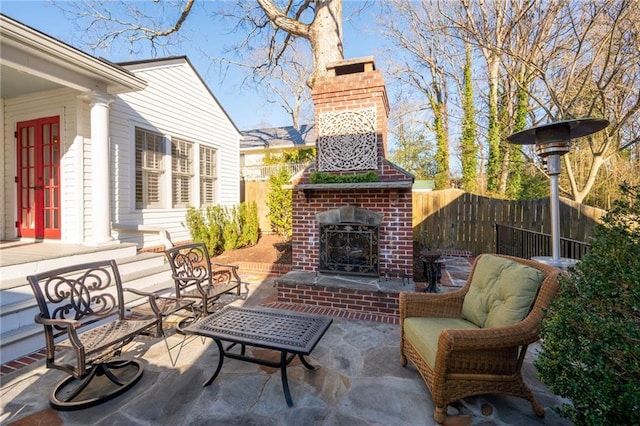 view of patio / terrace with an outdoor living space with a fireplace and fence