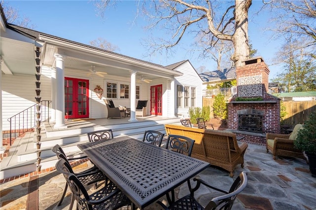 view of patio / terrace with french doors, outdoor dining area, an outdoor living space with a fireplace, ceiling fan, and fence