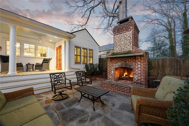 view of patio with an outdoor living space with a fireplace, ceiling fan, and fence