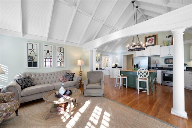 living area with decorative columns, visible vents, wood finished floors, a chandelier, and a wealth of natural light