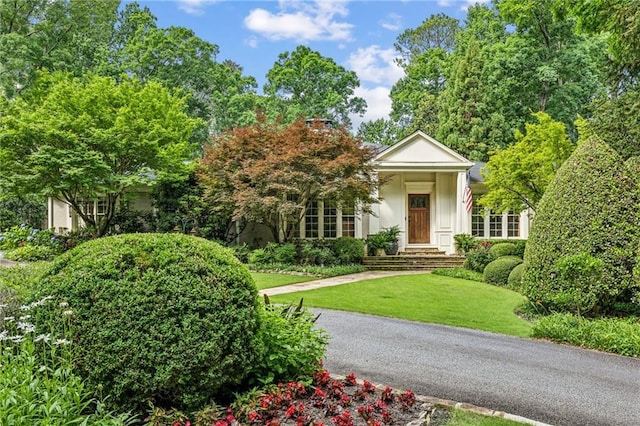 neoclassical home featuring a front lawn