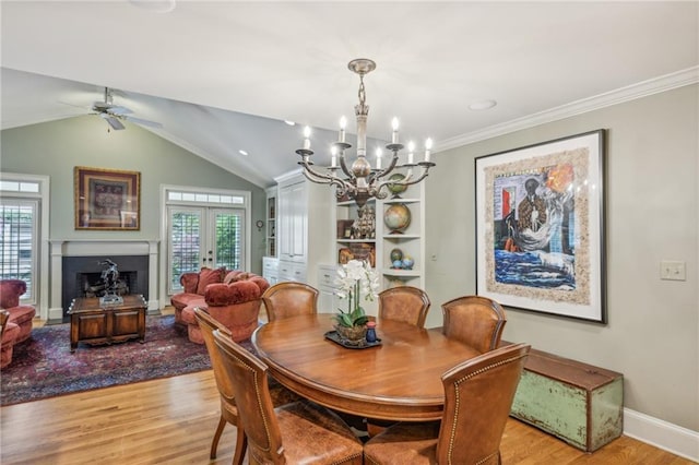 dining room featuring lofted ceiling, french doors, light wood-type flooring, ornamental molding, and ceiling fan with notable chandelier