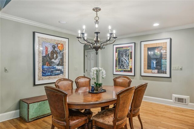 dining area with ornamental molding, a notable chandelier, and light hardwood / wood-style flooring