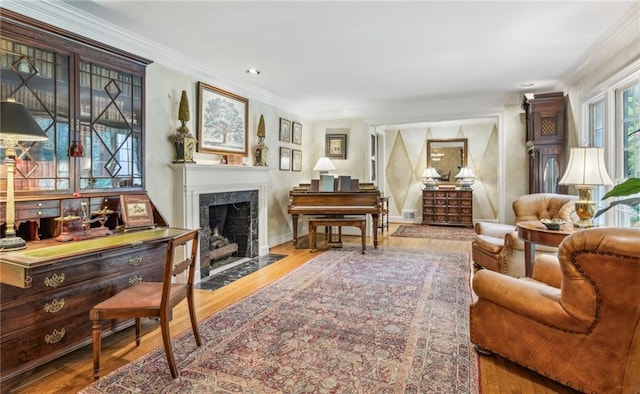 living area featuring a fireplace, ornamental molding, and light hardwood / wood-style floors