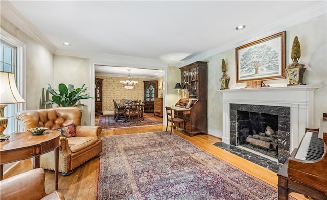 living room featuring a high end fireplace, an inviting chandelier, ornamental molding, and hardwood / wood-style flooring