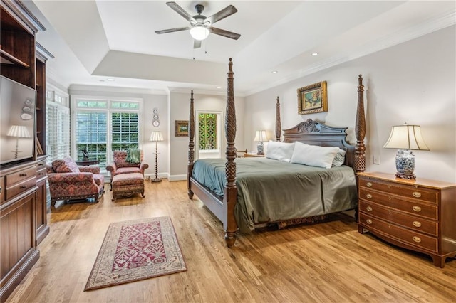 bedroom featuring a raised ceiling, ceiling fan, crown molding, and light hardwood / wood-style flooring