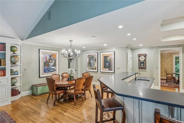 dining room with sink, a chandelier, ornamental molding, and built in features