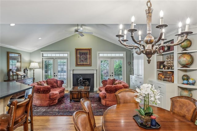 dining room with lofted ceiling, french doors, wood-type flooring, and ceiling fan with notable chandelier