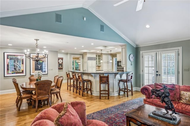 living room with vaulted ceiling, ornamental molding, french doors, light hardwood / wood-style flooring, and ceiling fan with notable chandelier