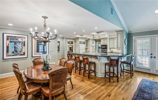 dining room featuring lofted ceiling, a notable chandelier, crown molding, and light hardwood / wood-style flooring