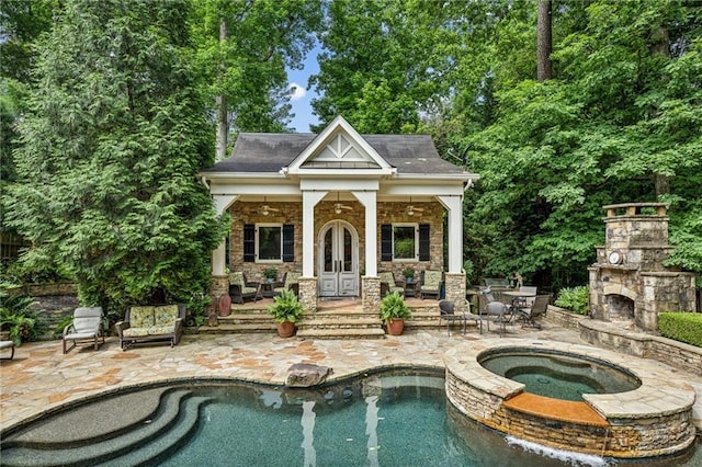 view of pool featuring a patio area, an outdoor stone fireplace, an in ground hot tub, and an outdoor structure