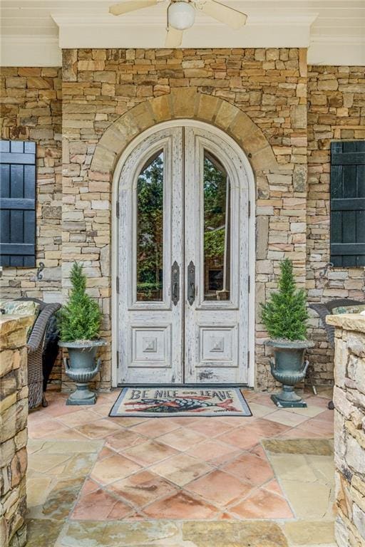 view of exterior entry featuring ceiling fan and french doors